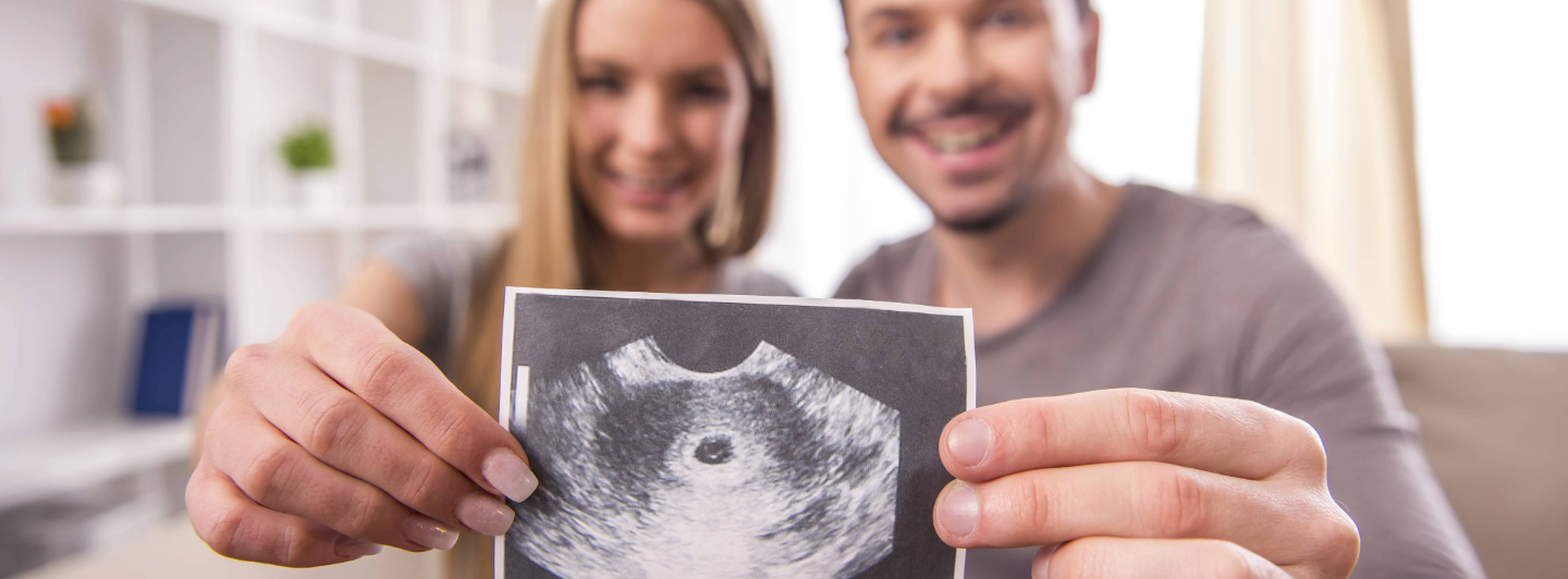 Pareja embarazada mostrando una ecografía del bebé, cuidado prenatal y preparación para un embarazo saludable.