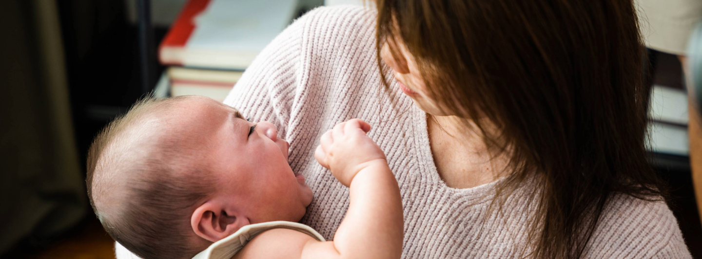 Bebé llorando en brazos de su madre, mostrando irritabilidad por cólicos, gases y llanto excesivo.