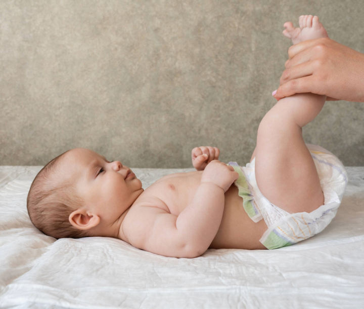 Bebé con expresión de molestia en brazos de un adulto, acompañado de texto sobre qué hacer en caso de diarrea en bebés y cómo identificar causas y soluciones.