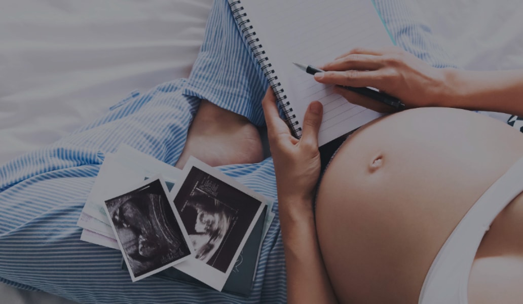 Mujer embarazada en casa junto a ecografías, planificación de nutrición durante el embarazo y cuidado prenatal en casa.