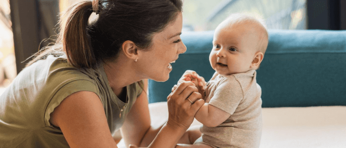 Mother Smiling at Baby While Holding Hands Indoors