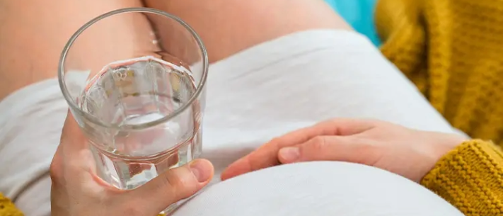 Top view of pregnant woman holding a glass of water 