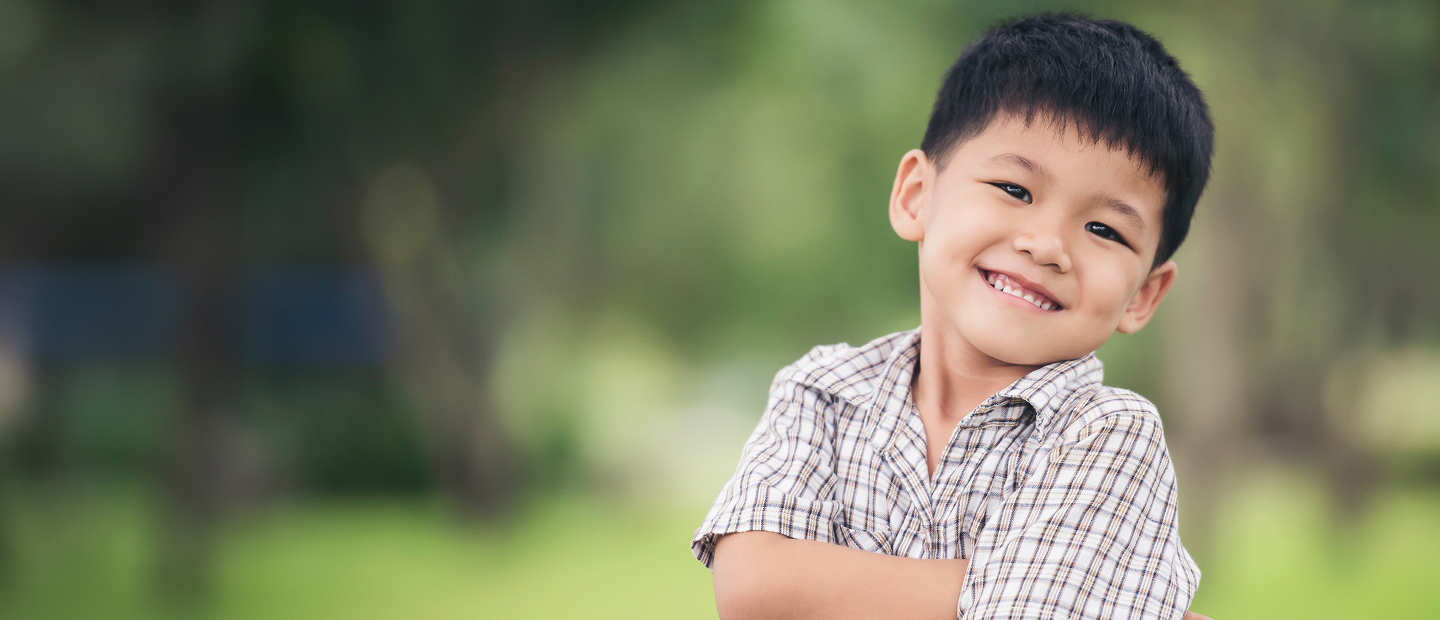 Young School-Age Boy Smiling With Arms Crossed In A Bright Setting