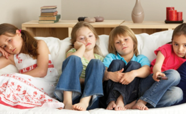 Four young siblings on couch looking tired or upset