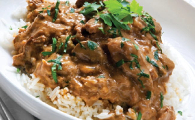 Sweet beef steak with baby corn served with rice on white platter