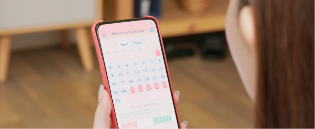 Back view of woman reading her ovulation tracker on phone