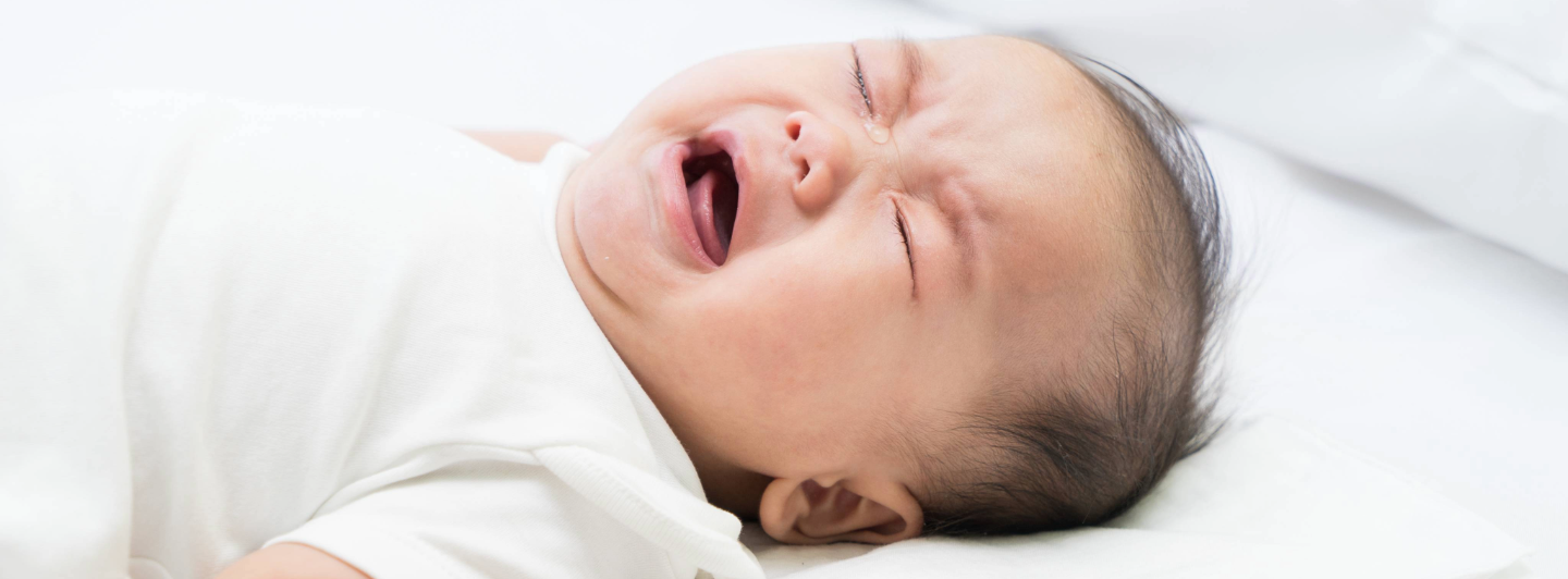 Bebé llorando por molestias digestivas, representando síntomas de estreñimiento o diarrea como señales de alerta.