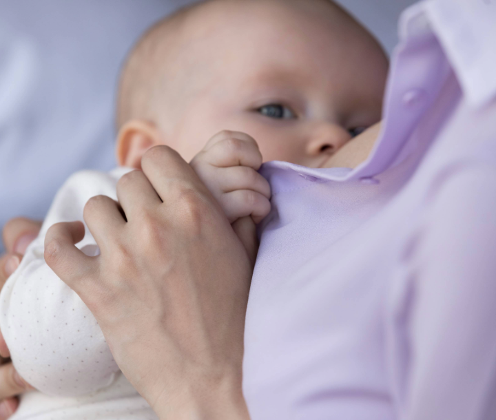 Madre cargando a su bebé envuelto en manta, junto a texto sobre problemas de alimentación comunes en los bebés.