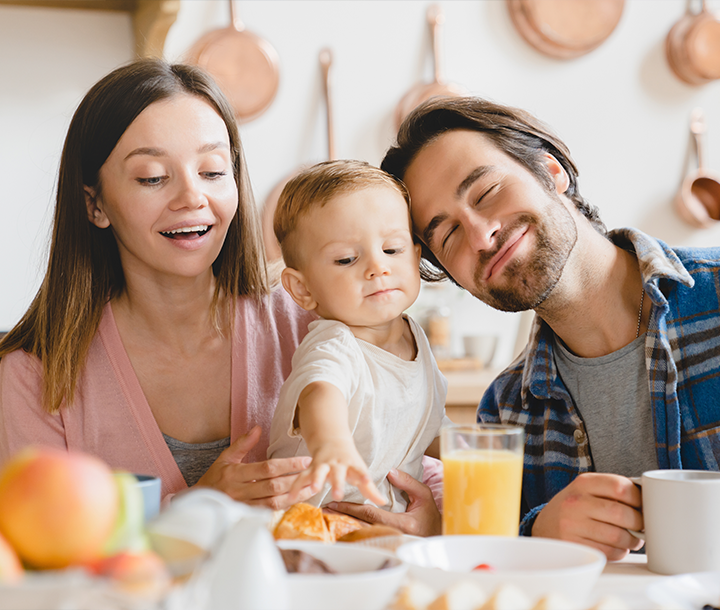 Padres alimentando a su bebé en casa, mostrando el trabajo en pareja y la importancia de la participación familiar en la nutrición.