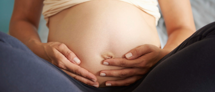 Pregnant woman stroking her belly in sitting position