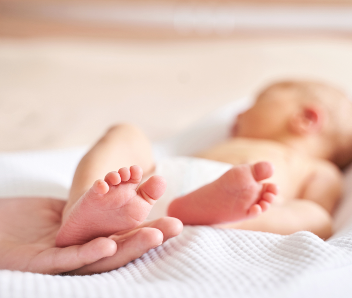 Mano de adulto sosteniendo el pie de un bebé prematuro, símbolo de cuidado y protección en los primeros días de vida.