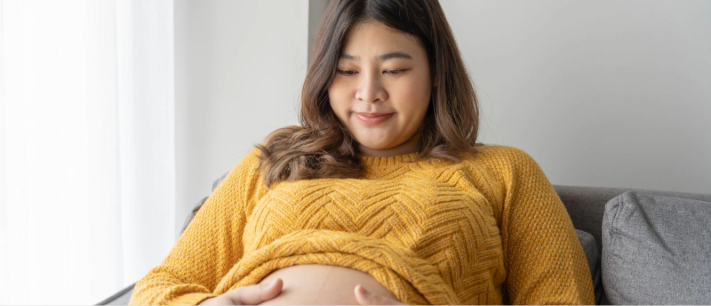 Husband hugging pregnant wife as they both sit on a bed