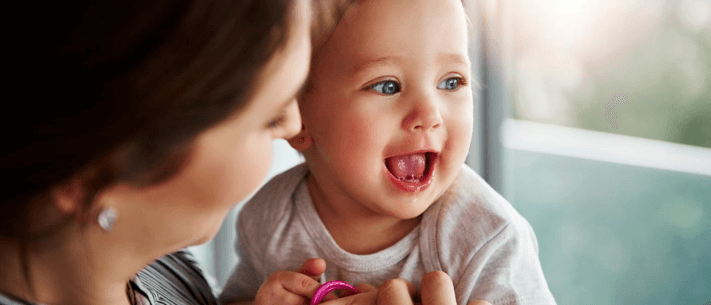 Mother Looking at Her Baby Holding Pink Pacifier