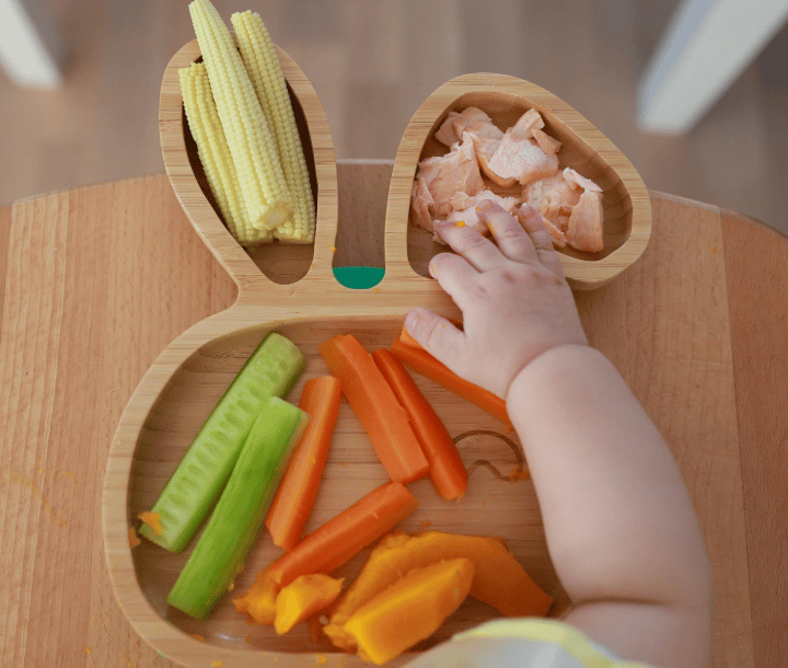 Plato de madera con vegetales y camarones como fuente de DHA y nutrientes para niños.