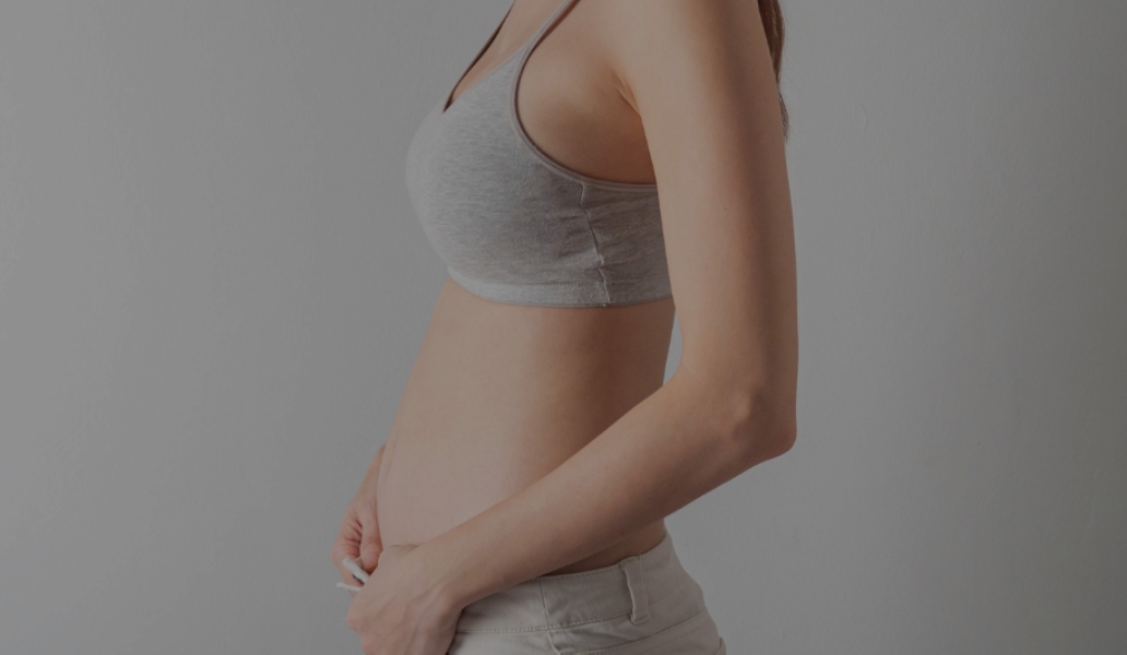 Mujer en las primeras semanas de embarazo tocando su vientre, símbolo de nutrición y cuidado prenatal desde el inicio.