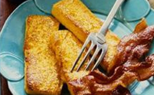 French toast pieces with bacon on blue platter with fork