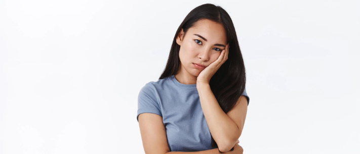 Woman standing with arm on chin looking worried