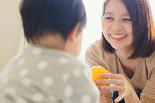 Mother And Child Smiling While Looking At A Tablet On Kitchen Counter, With Salad And Ingredients Nearby