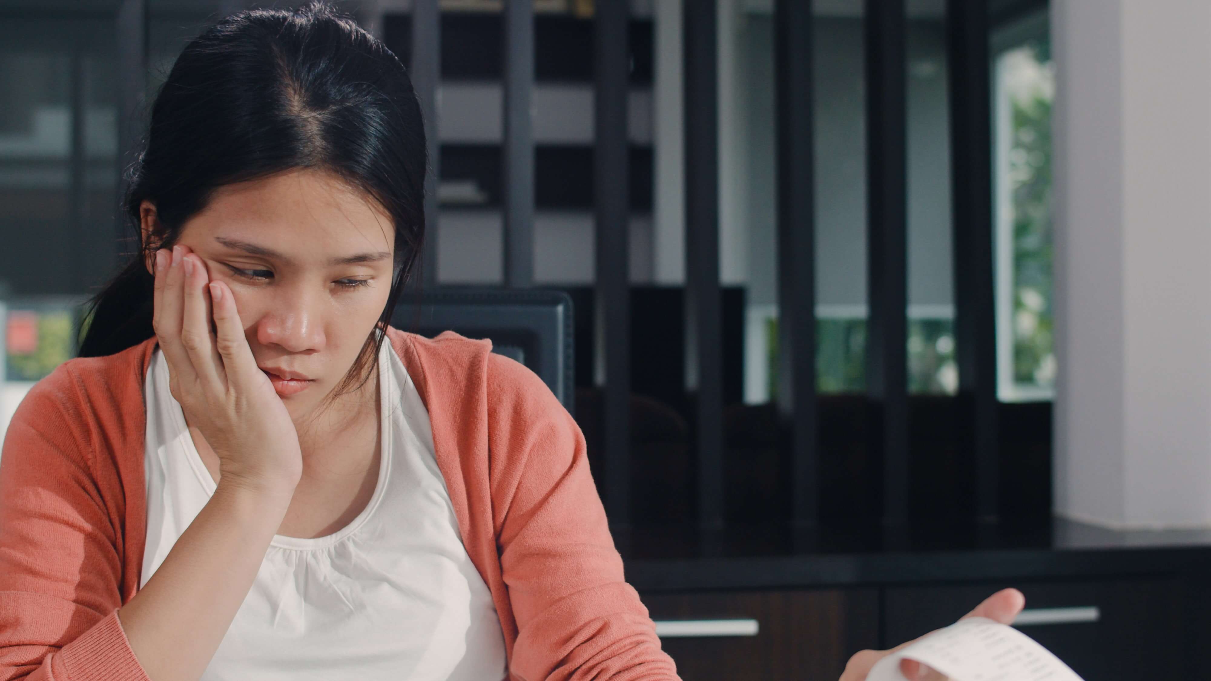 Woman Appears Stressed Reviewing Receipt at Home