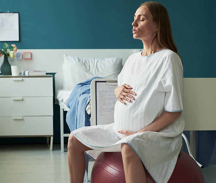 Mujer embarazada realizando ejercicios suaves en sala de parto para facilitar el trabajo de parto y aliviar molestias.
