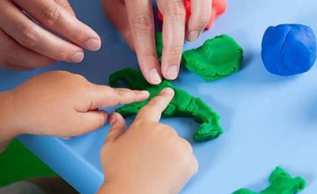 Close up on child’s and mother’s hands playing with clay