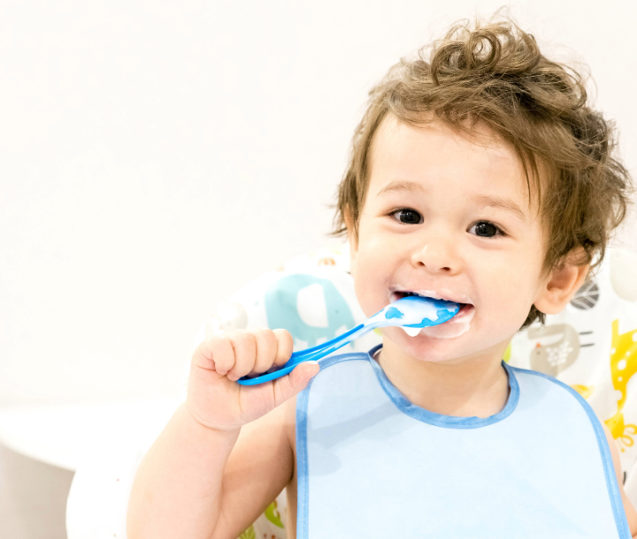 Niño pequeño sentado hojeando un libro ilustrado, acompañado de texto sobre la adaptación y el desarrollo a ritmos distintos en cada bebé.