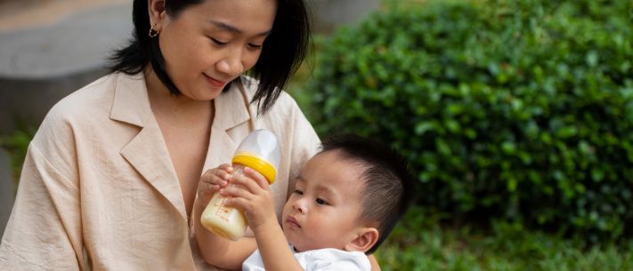 Mother kissing baby drinking milk from bottle