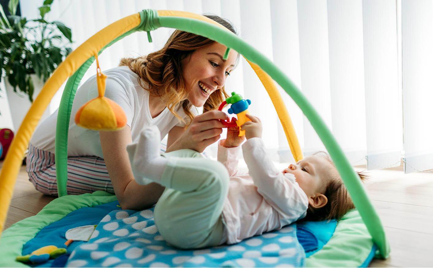 Mother Engaging with Son on Play Mat with Activity Gym