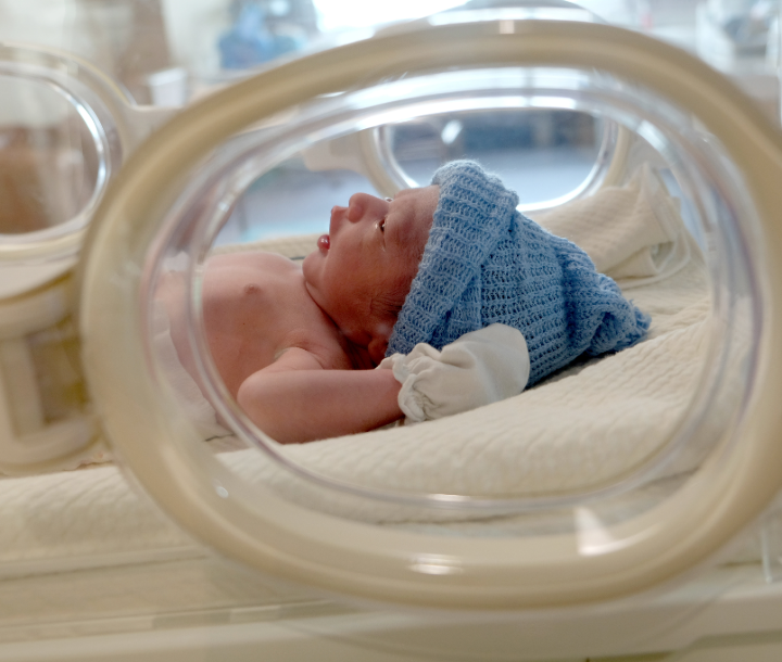 Bebé prematuro con gorro y mitones.