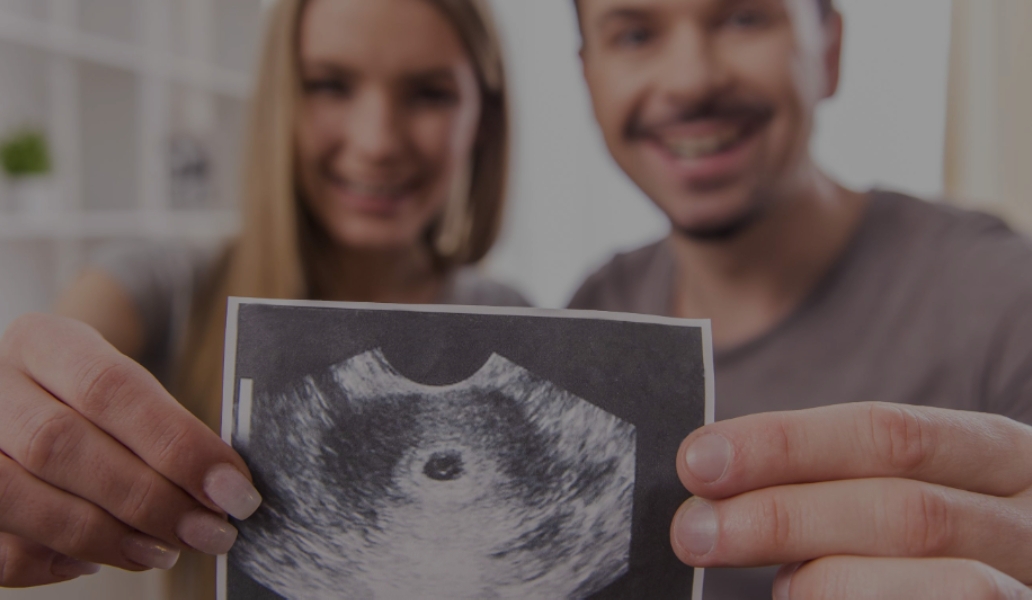 Pareja embarazada mostrando una ecografía del bebé, cuidado prenatal y preparación para un embarazo saludable.