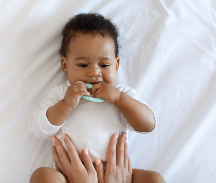 Bebé recostado con expresión de incomodidad mientras un adulto le sostiene las piernas, acompañado de texto sobre cómo los gases afectan a los bebés.