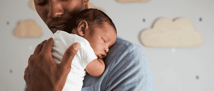 Father Holding Sleeping Baby, Both with Gentle Expressions, Against White Background with Cloud Decorations