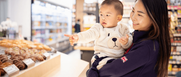 Mom Carrying Her Son In Supermarket Bread Section