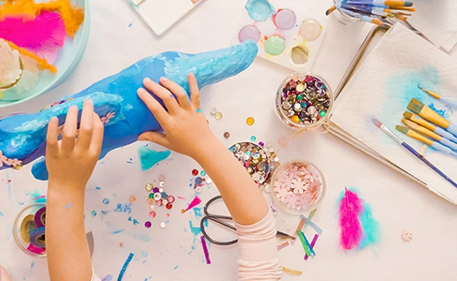 Top shot of a child’s hands playing with various arts and crafts
