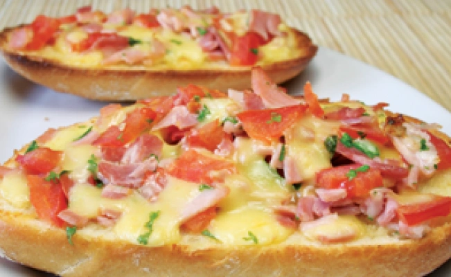Two slices of ham and mushroom open-faced sandwiches served on white platter on wooden surface