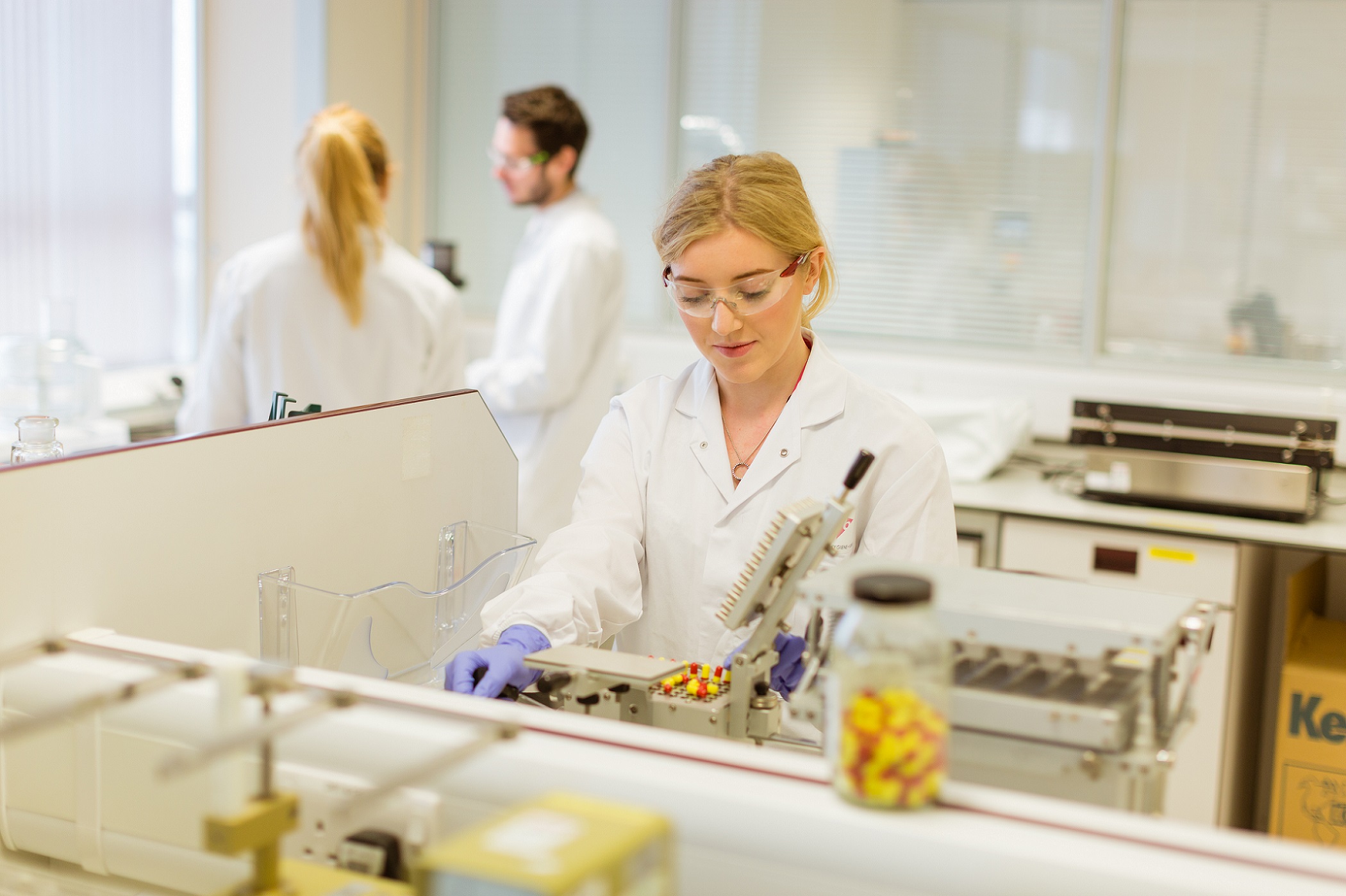 Scientist working in a laboratory with colleagues in the background