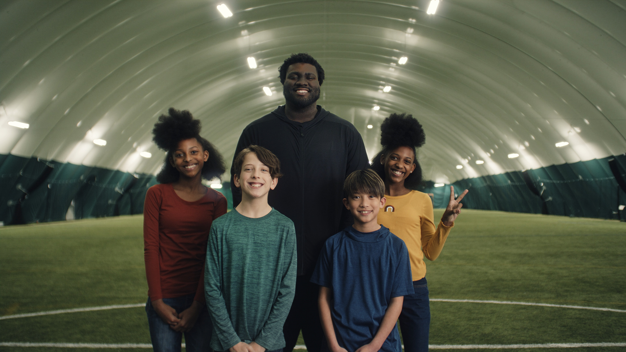 Coach and children smiling together on an indoor sports field
