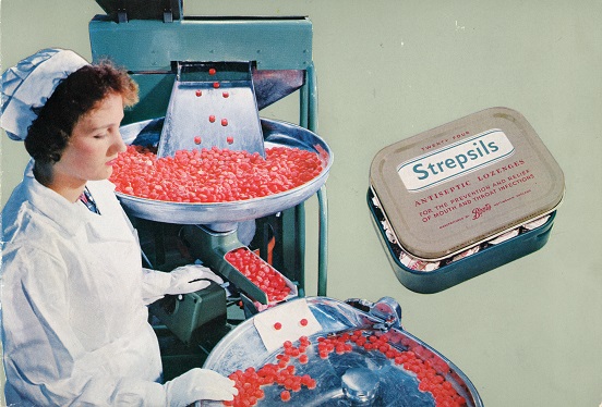 Worker sorting red lozenges on a production line with a Strepsils tin shown.