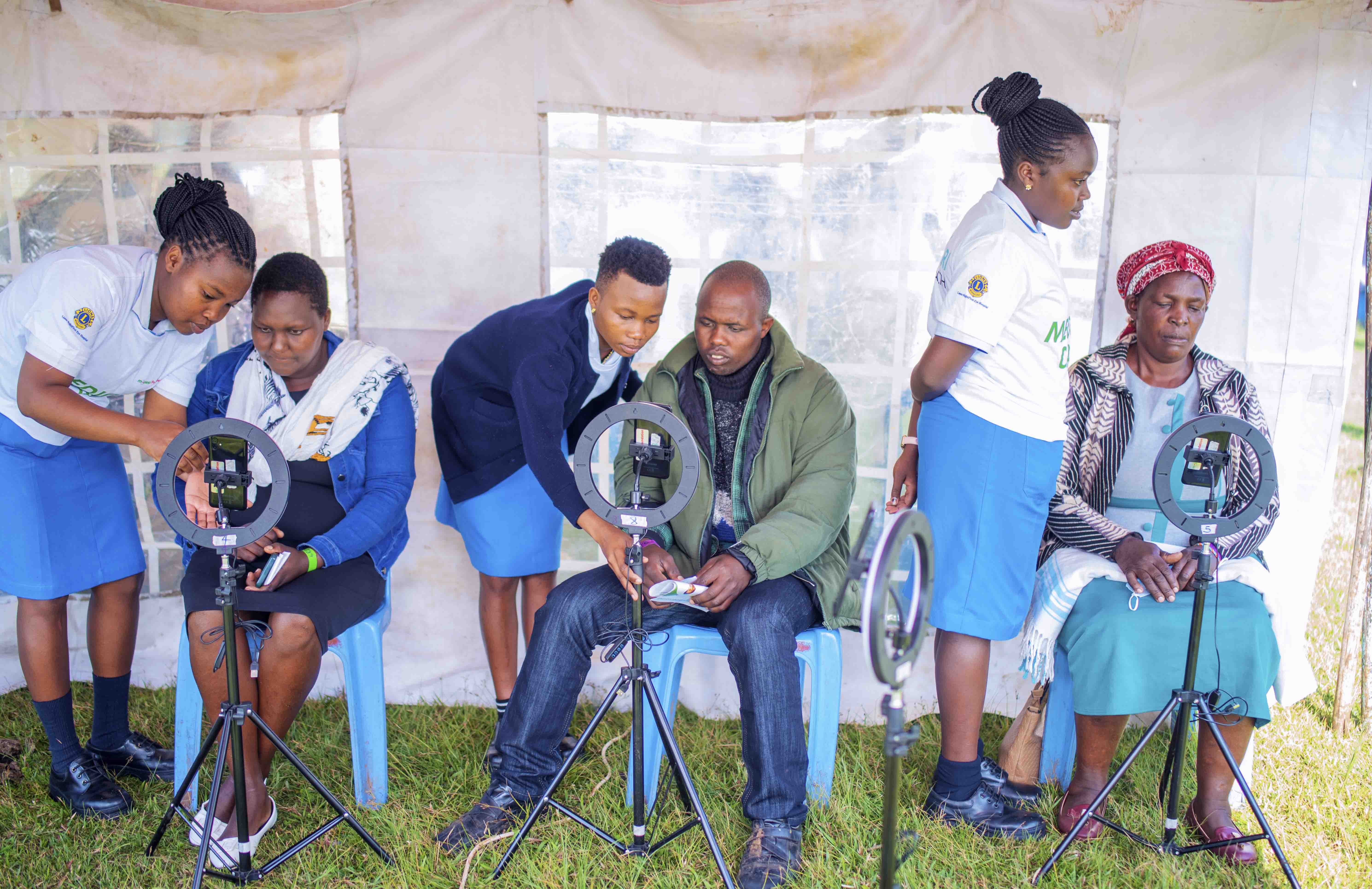 People using smartphones with ring lights in an outdoor setup.