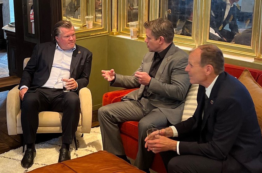 Three business leaders engaged in a discussion while seated together in a meeting lounge area