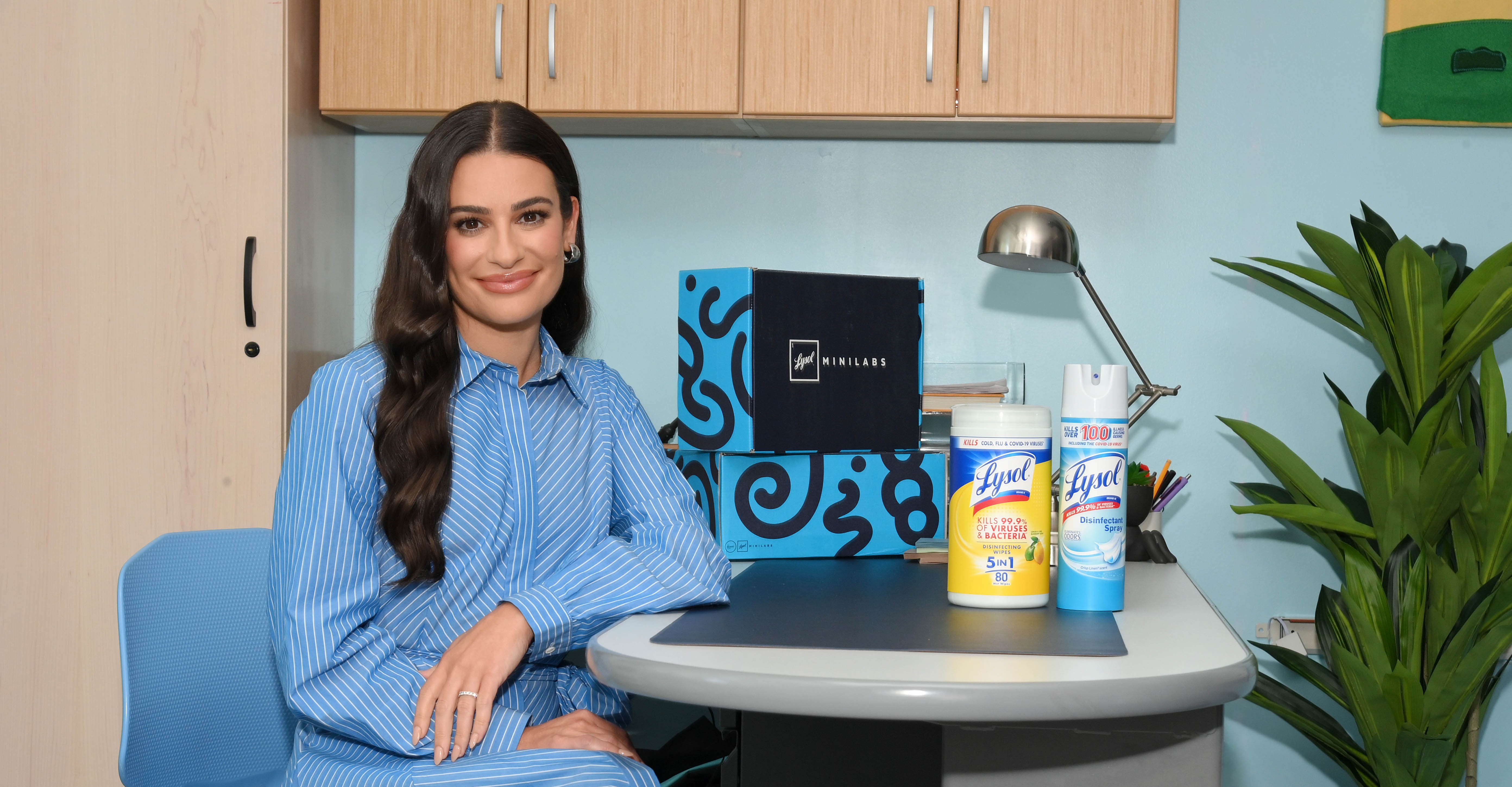 Woman seated at a desk beside Lysol products and branded boxes in an office setting