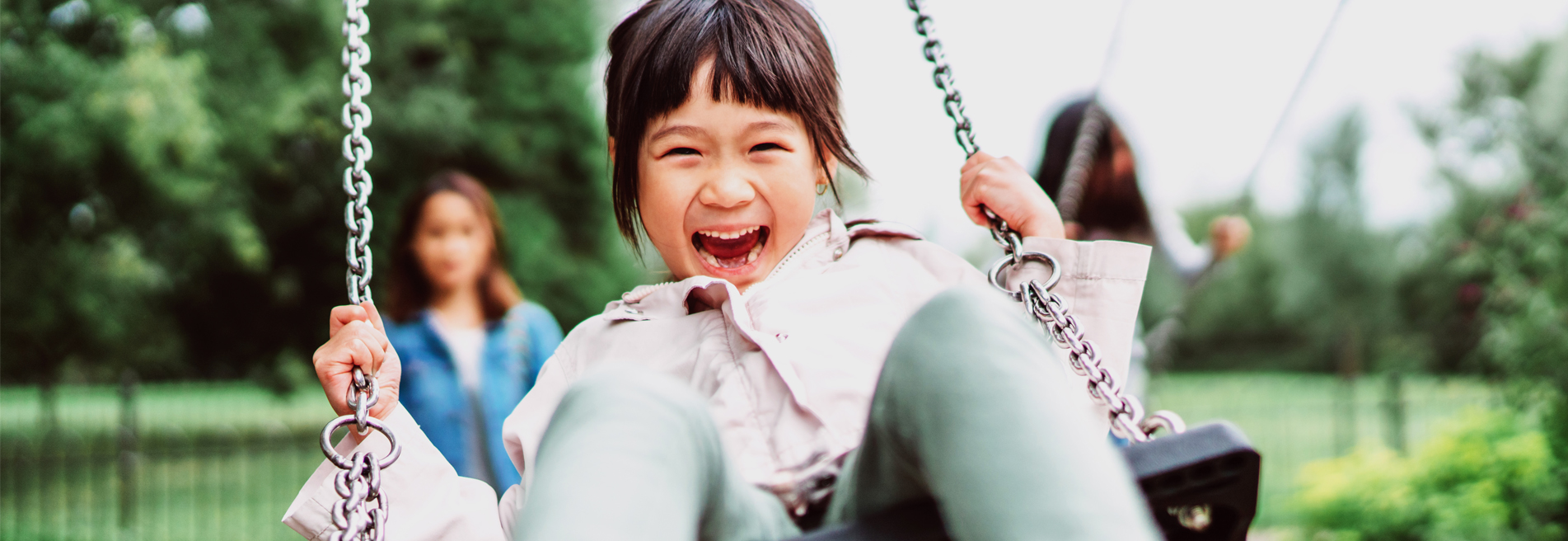 Child smiling while playing on a swing at a playground