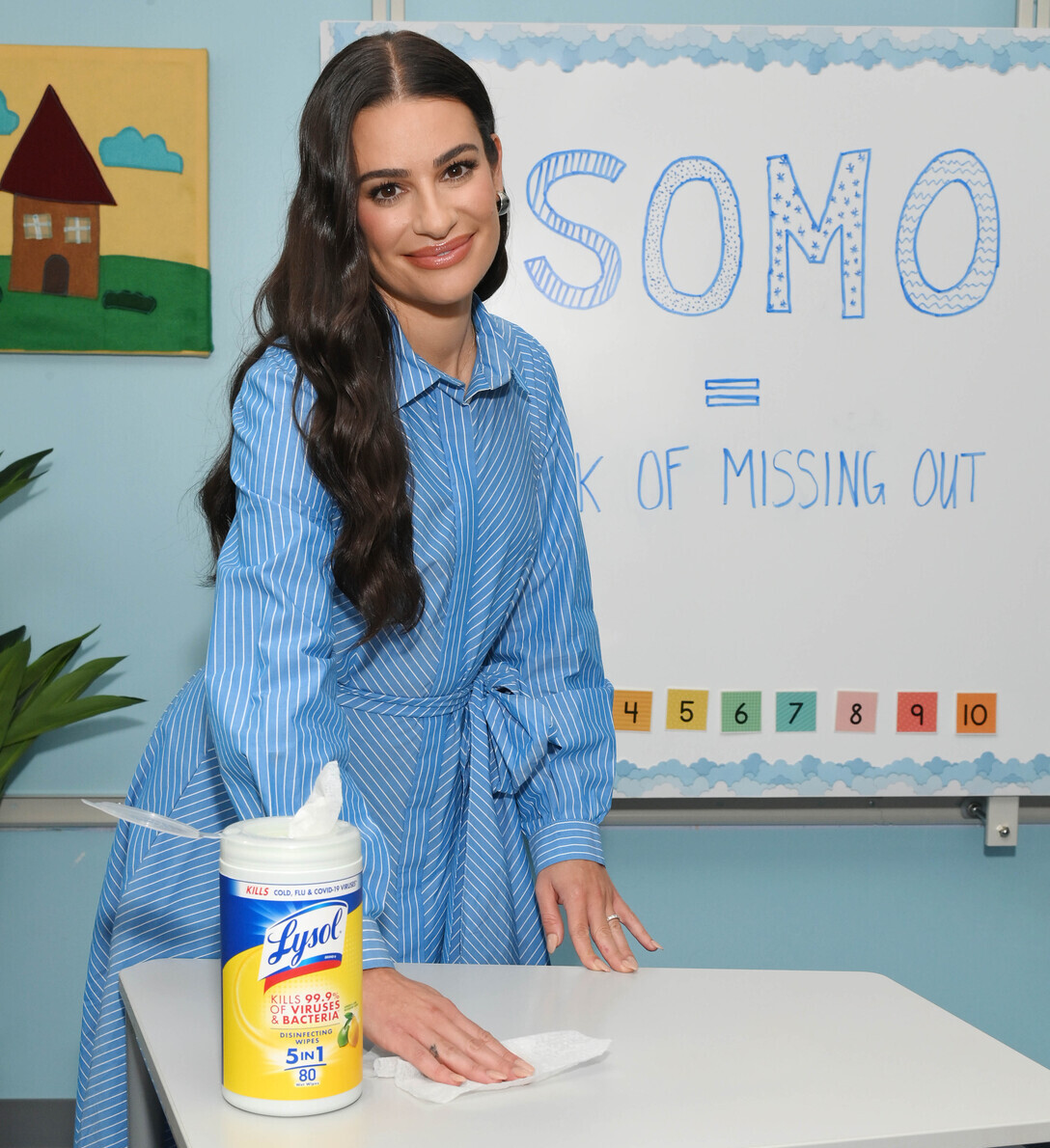 Woman cleaning a desk with Lysol wipes in a classroom setting