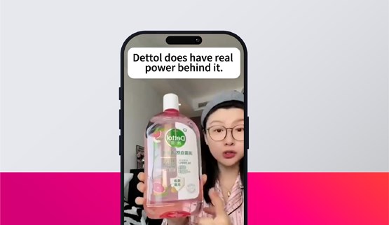 person holding a bottle of Dettol liquid inside a phone screen, with the text "Dettol does have real power behind it." displayed above.