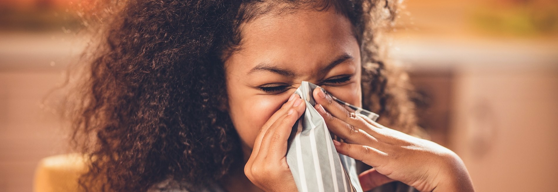 Person blowing their nose with a tissue, showing cold or flu symptoms