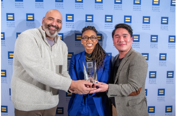 Three individuals posing with an award at a Human Rights Campaign event, celebrating recognition for LGBTQ+ workplace inclusion and equality initiatives