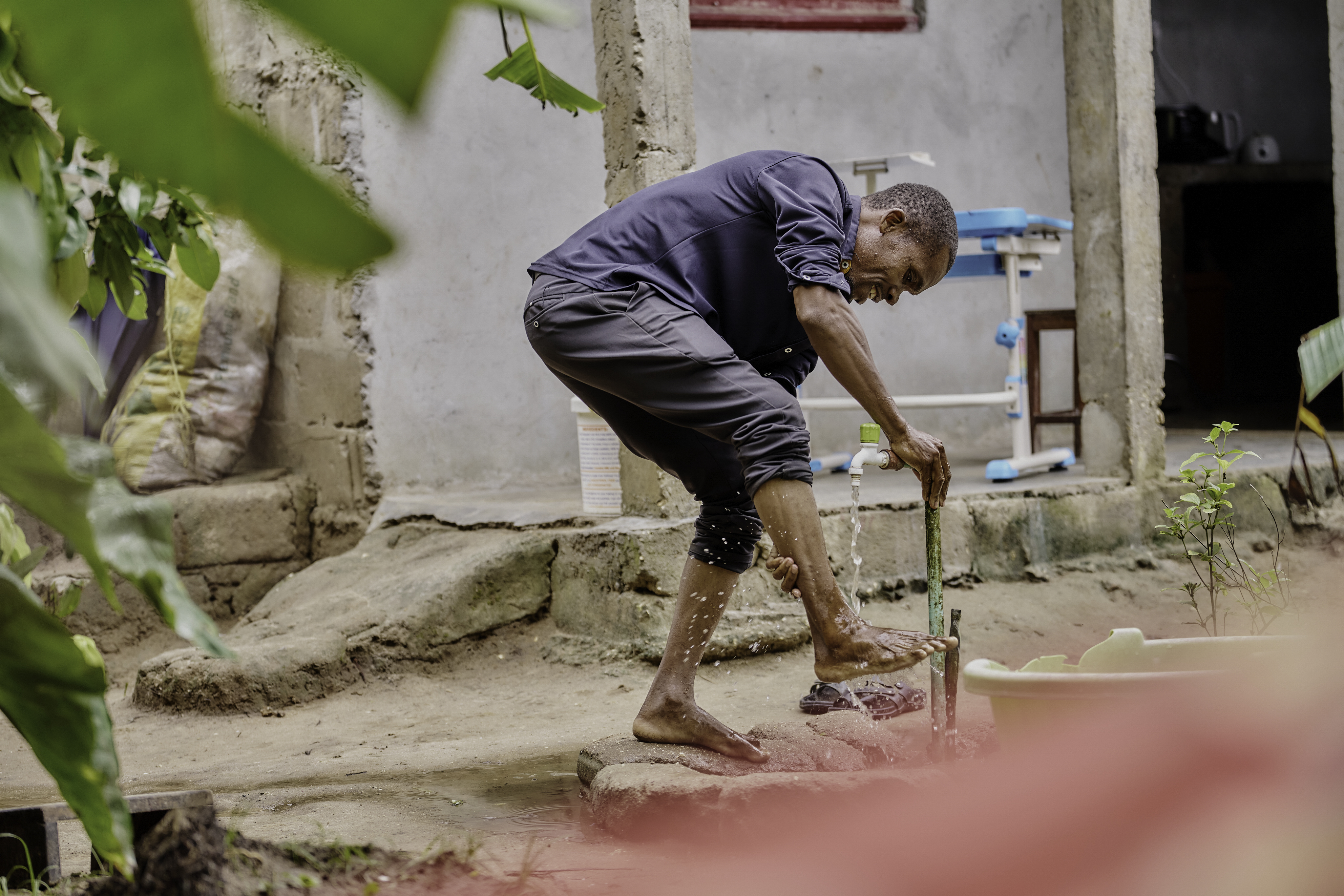 Man washing his foot with water from an outdoor tap