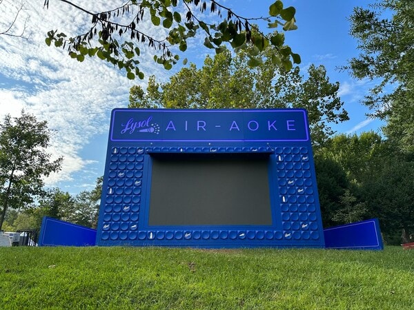 Outdoor Lysol Air-Aoke display installation on a grassy lawn surrounded by trees and blue sky