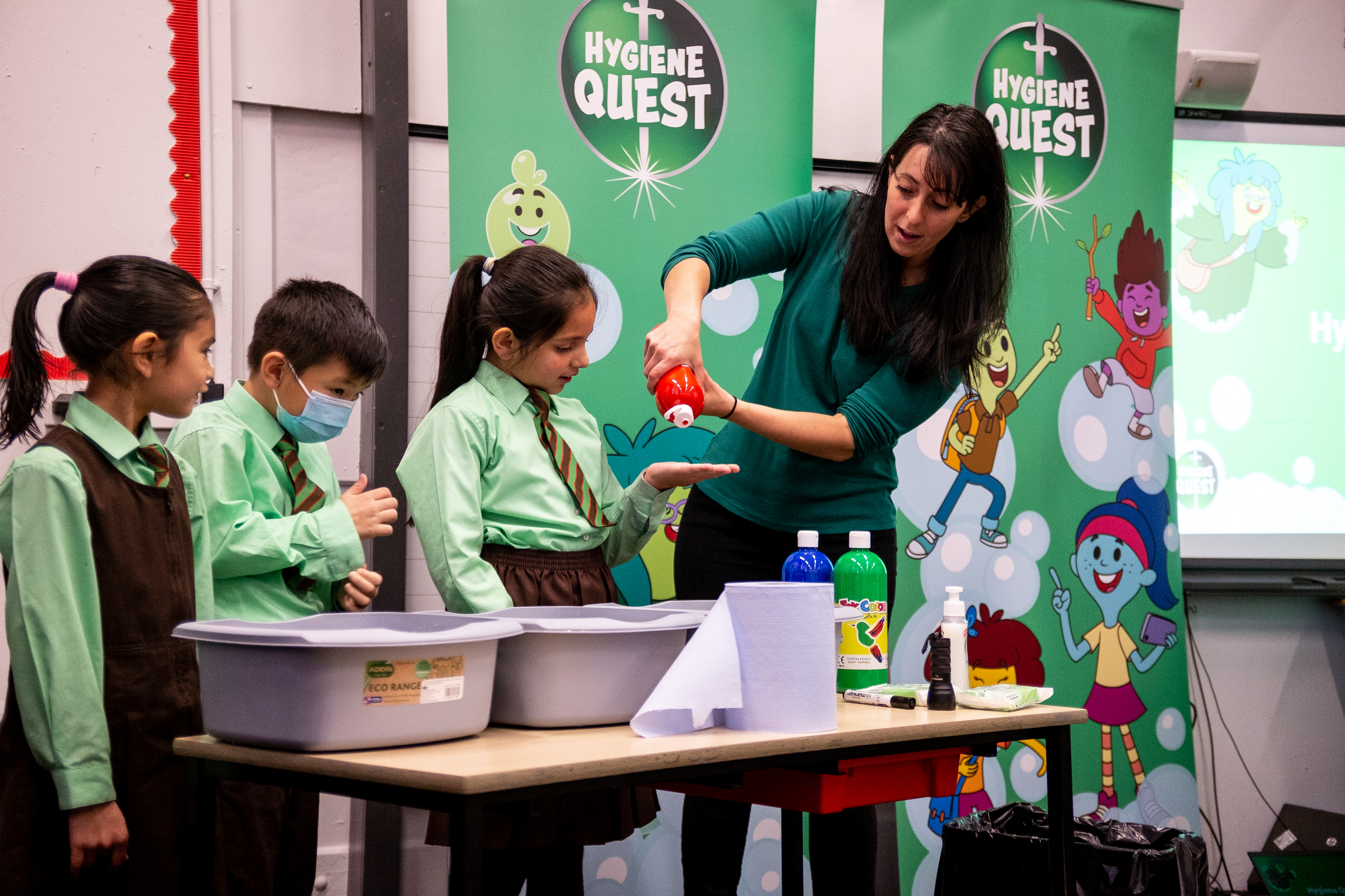 Teacher showing children how to wash hands in a classroom