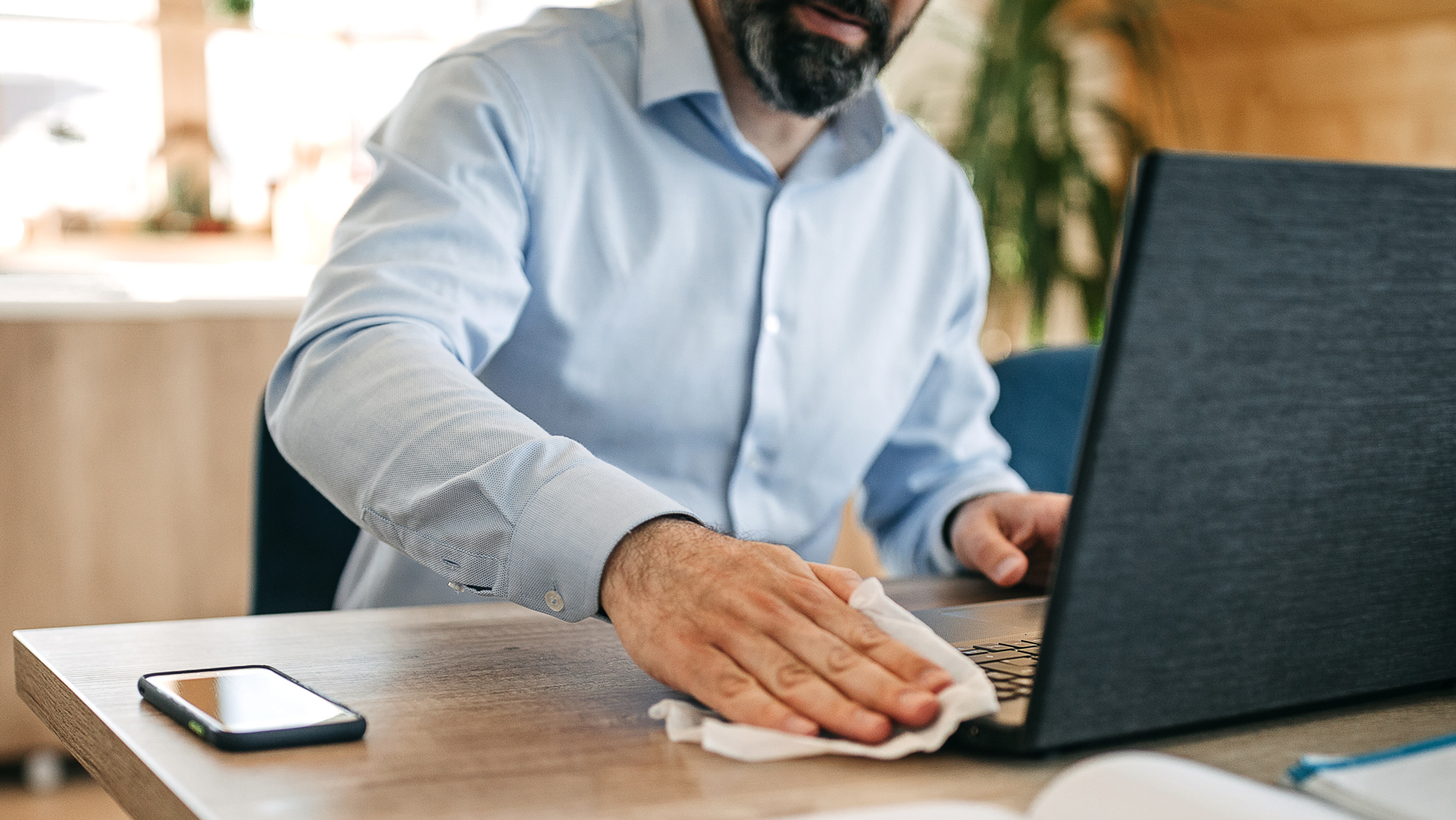 Man cleaning laptop with wipe